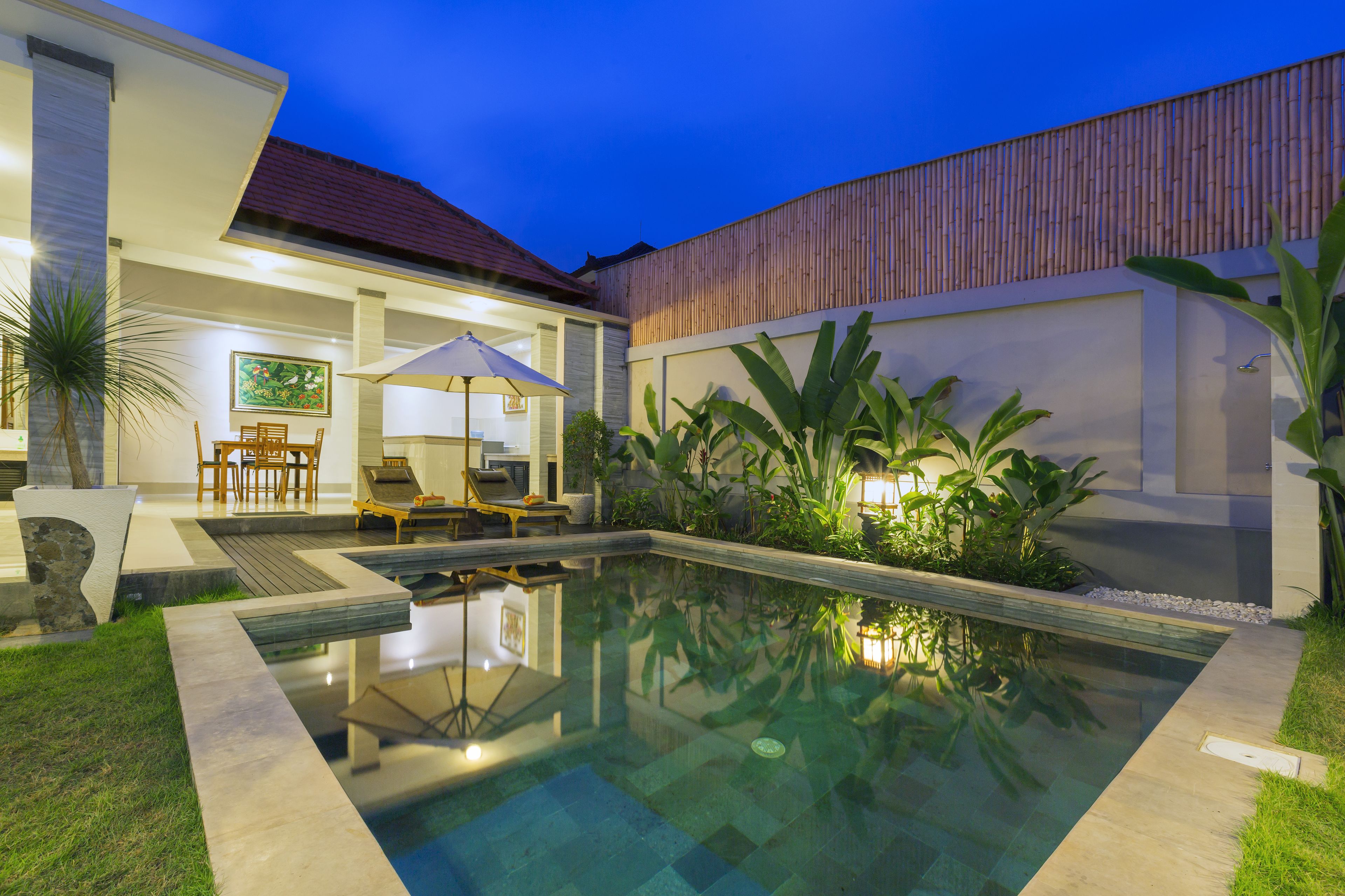 Un espace piscine extérieur moderne, comprenant un fauteuil de relaxation, un parasol et une table à manger.