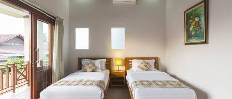 Habitación de hotel con dos camas de madera, un balcón y un cuadro en la pared.