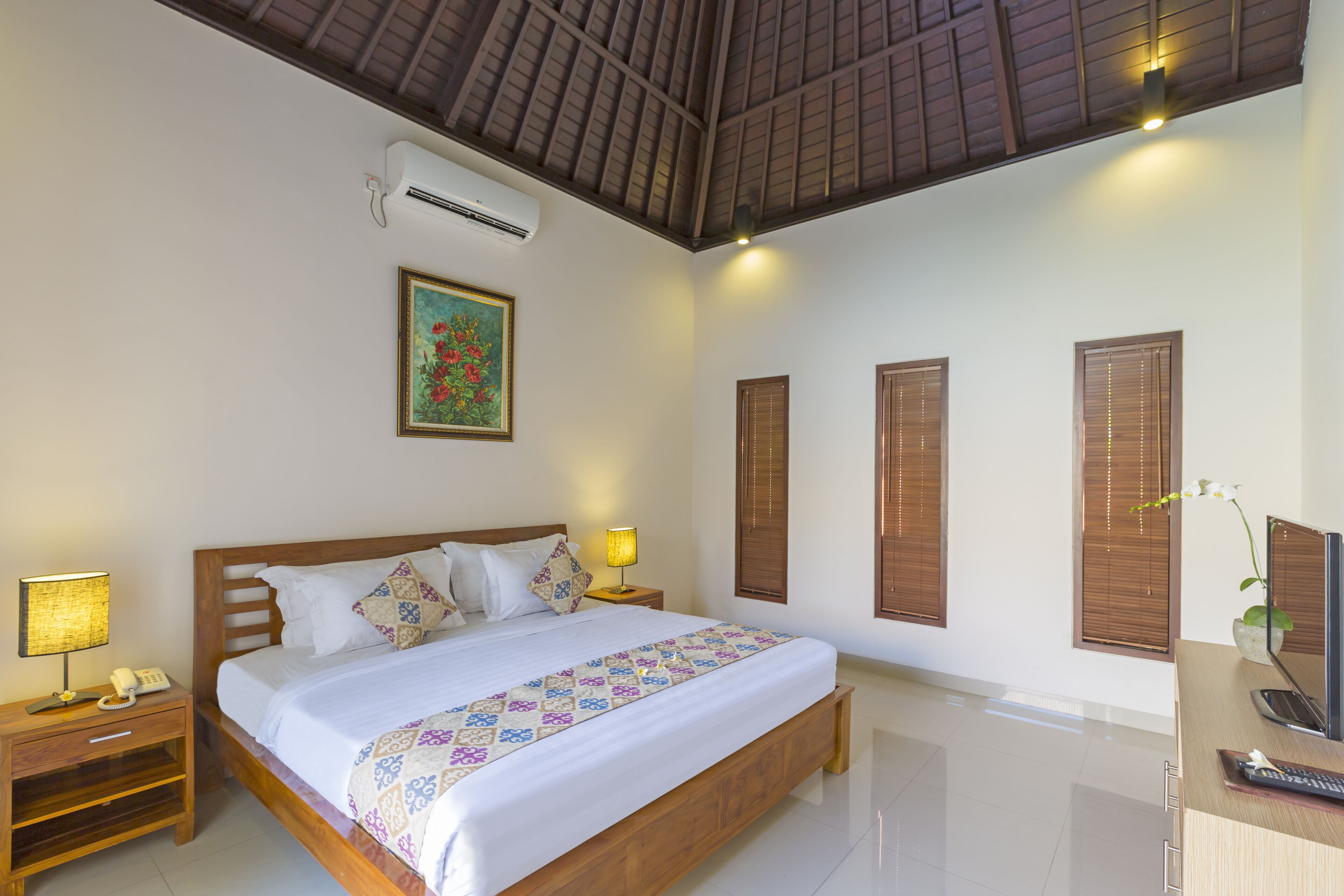 A hotel room with a wooden bed, bedside lamps, a desk with a computer, and a window with a view.