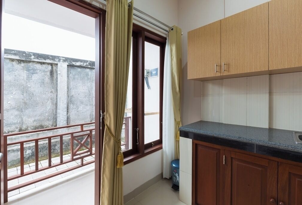 A kitchen with wooden cabinets, a black countertop, and a window with curtains.