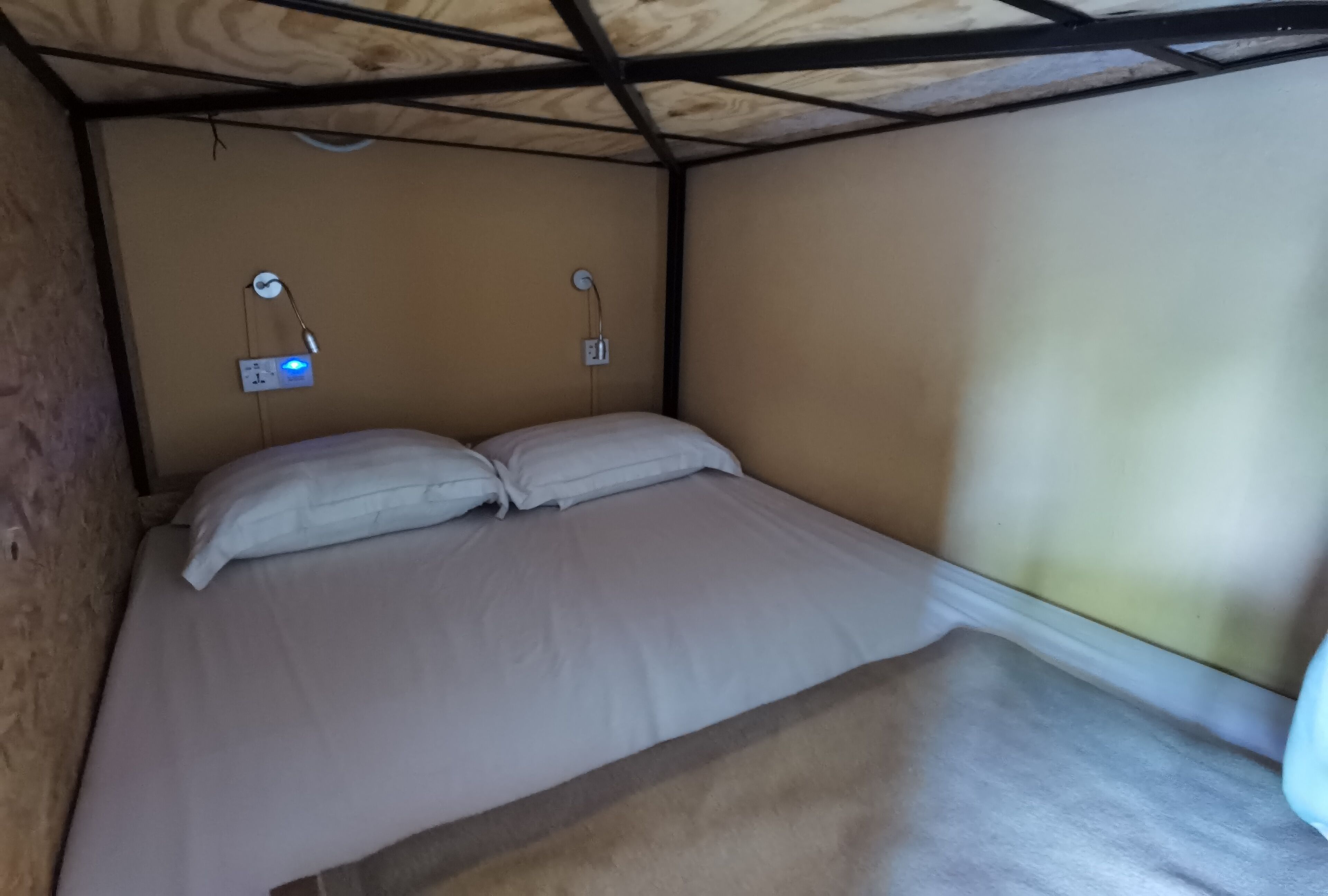 A single bed with white bedding in a room with wooden ceiling beams and beige walls.