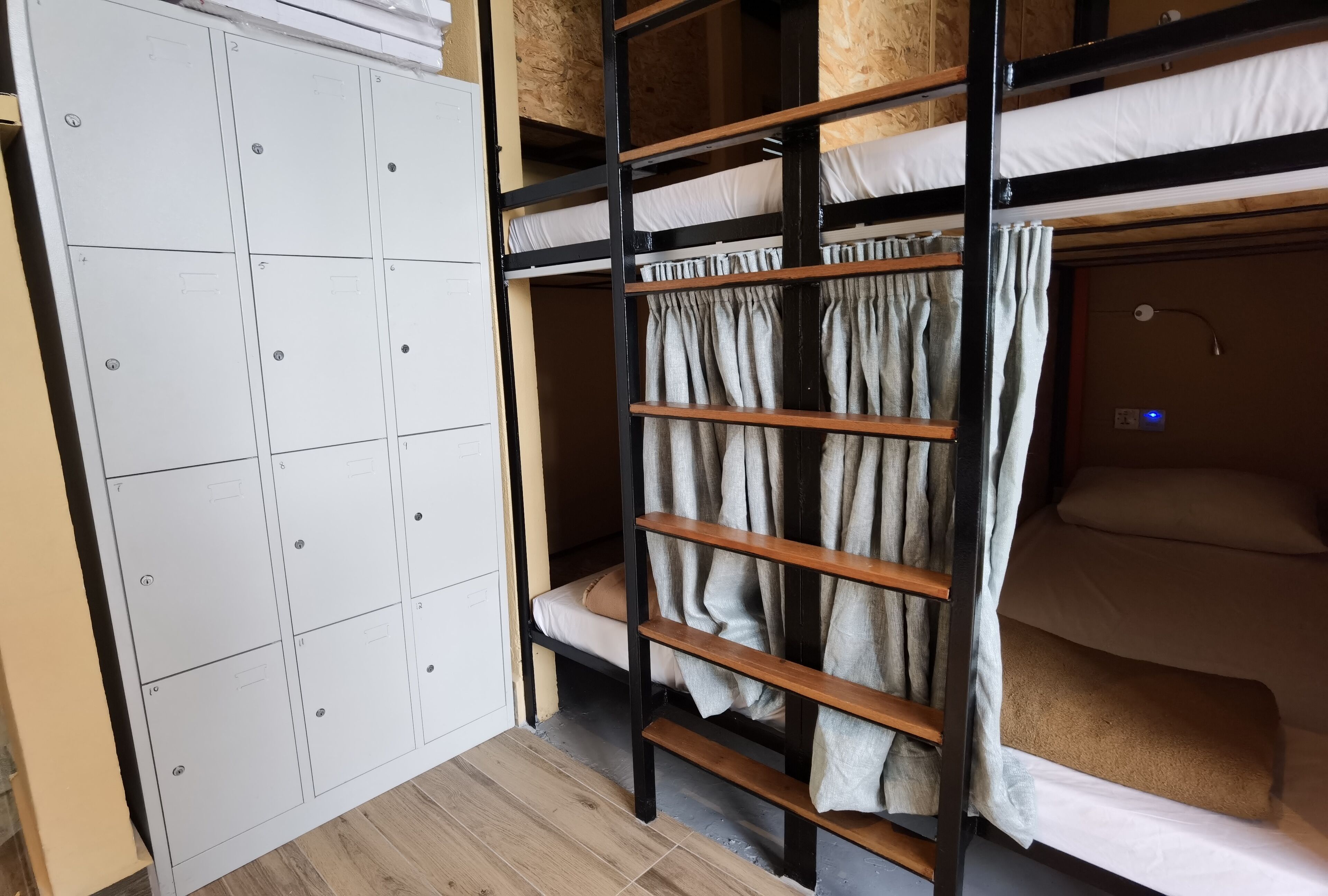 A bunk bed with a ladder, a white wardrobe, and a curtain.