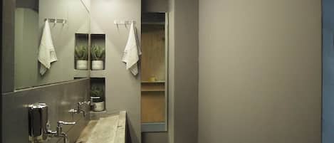 A modern bathroom with a large mirror, a sink, and two towel hooks.