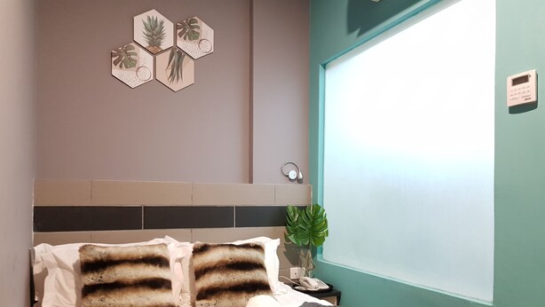 Een net opgemaakt bed met gestreepte kussens, een opgerolde handdoek en een waterfles op een dienblad.