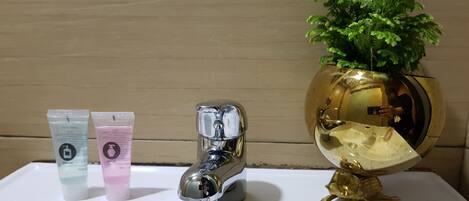 A bathroom sink with two toiletry tubes, a chrome faucet, and a decorative gold globe with a plant.