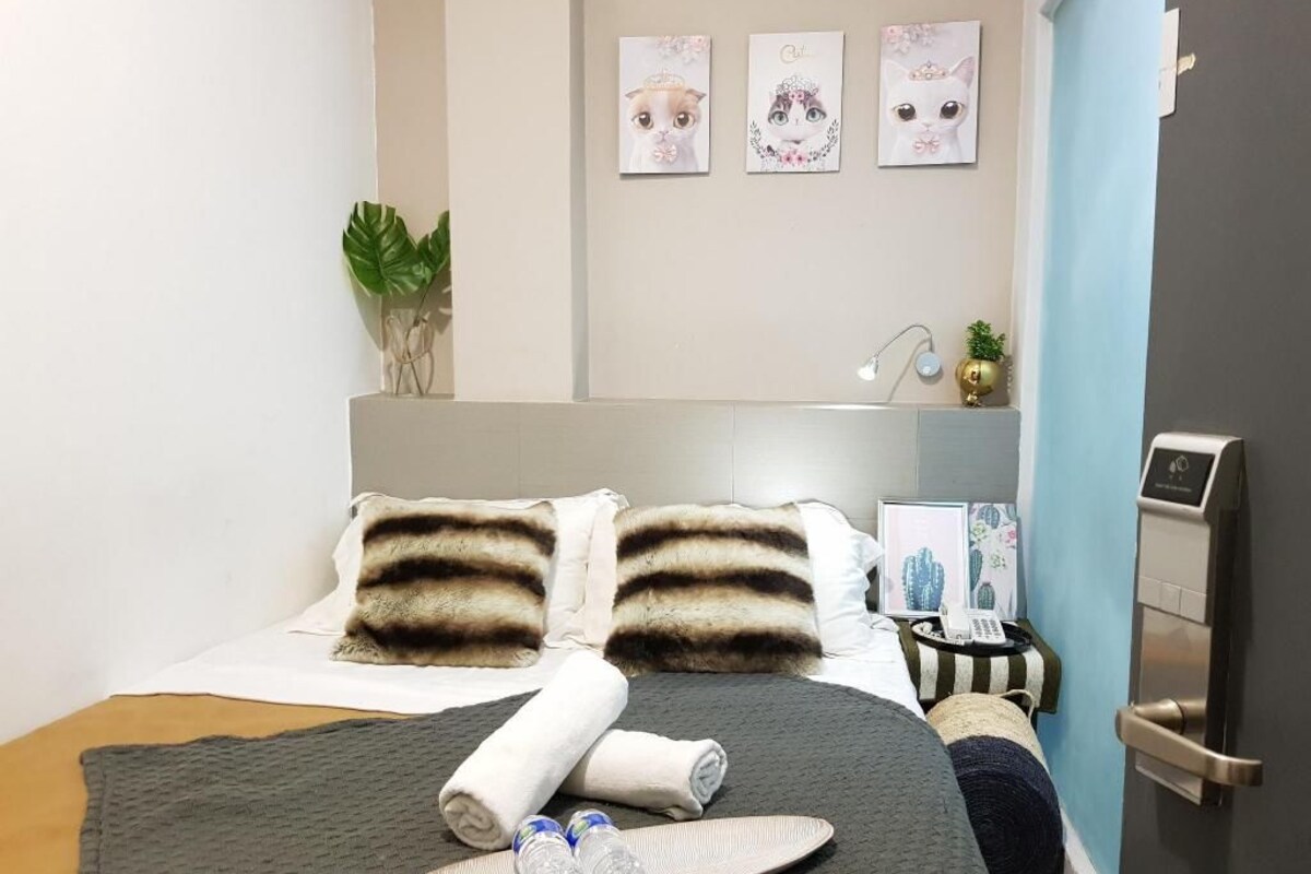 A hotel room with a bed, a bedside table with a lamp, and a wall-mounted artwork.