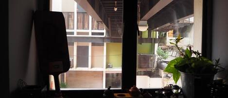 Una habitación con un ventanal grande, una mesa de madera con diversos objetos y una planta en maceta.