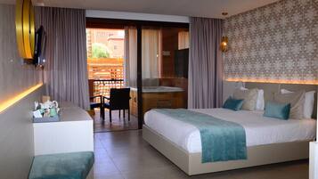 Habitación de hotel con cama, escritorio y silla. Tiene un balcón con vistas a edificios.