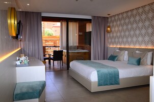 Habitación de hotel con cama, escritorio y silla. Tiene un balcón con vistas a edificios.