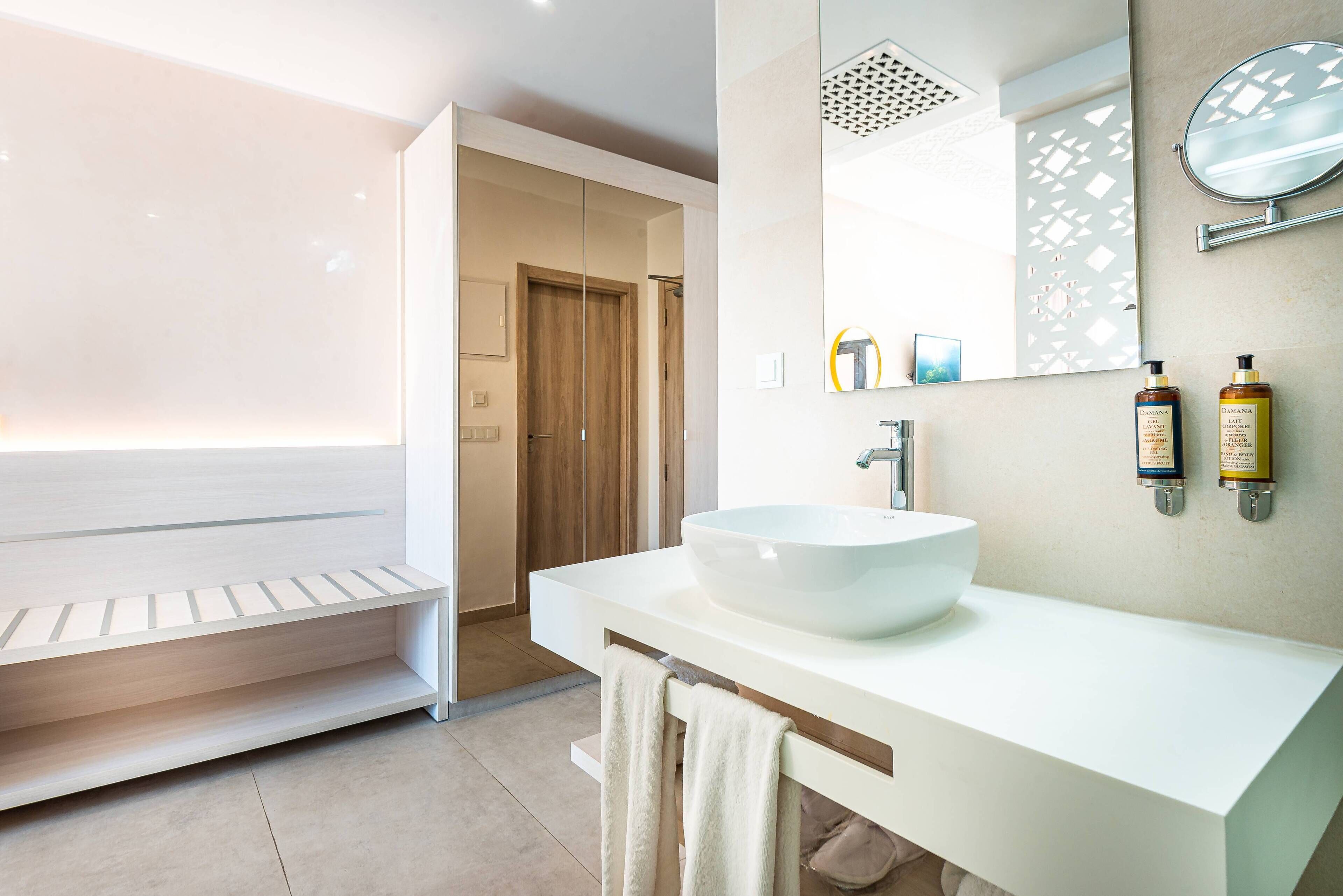 A modern bathroom with a large white sink, a mirror, and two bottles of shampoo.