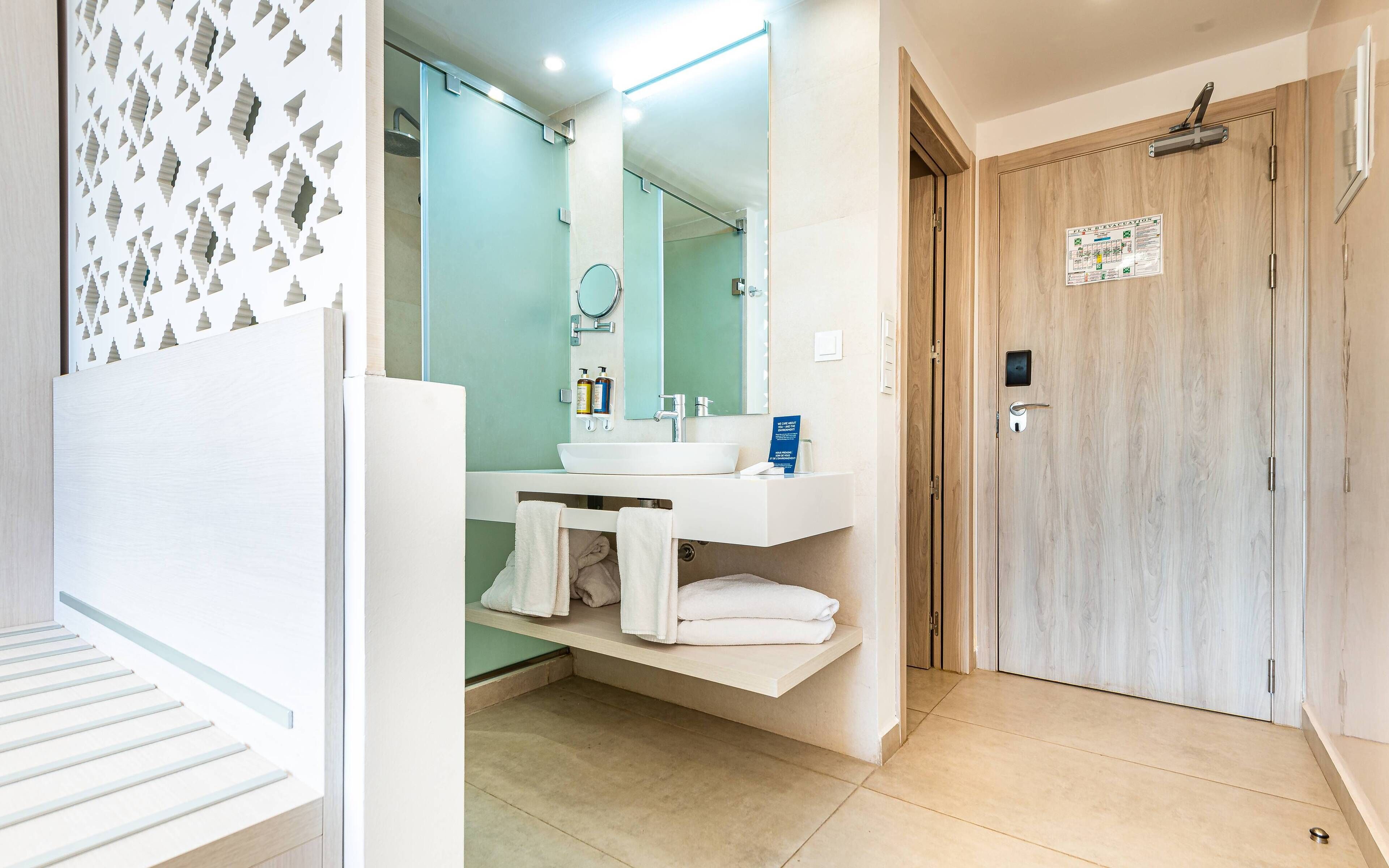 A modern bathroom with a white sink, mirror, and towel rack.