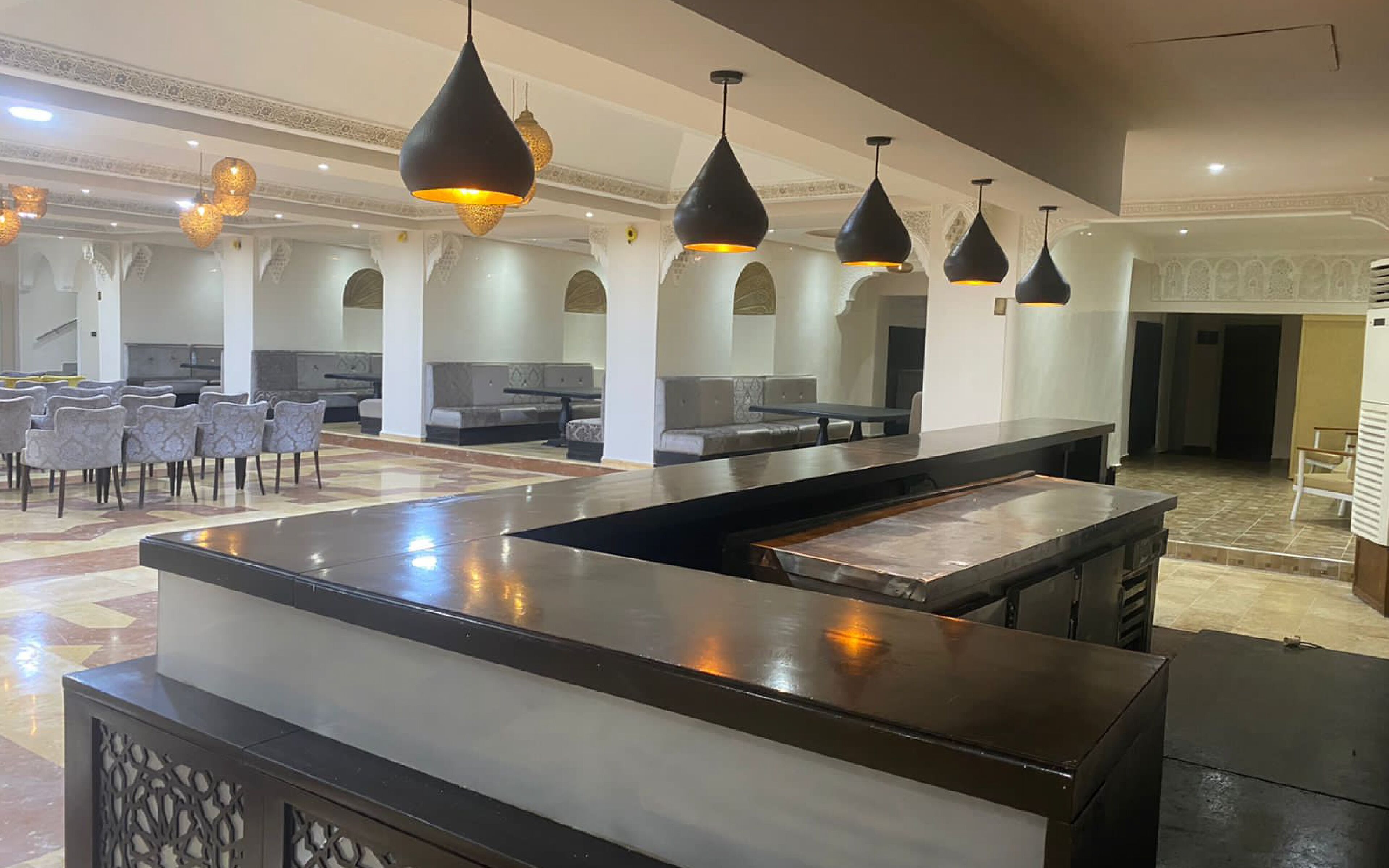 A spacious lobby with a central reception desk, seating areas, and decorative lighting.