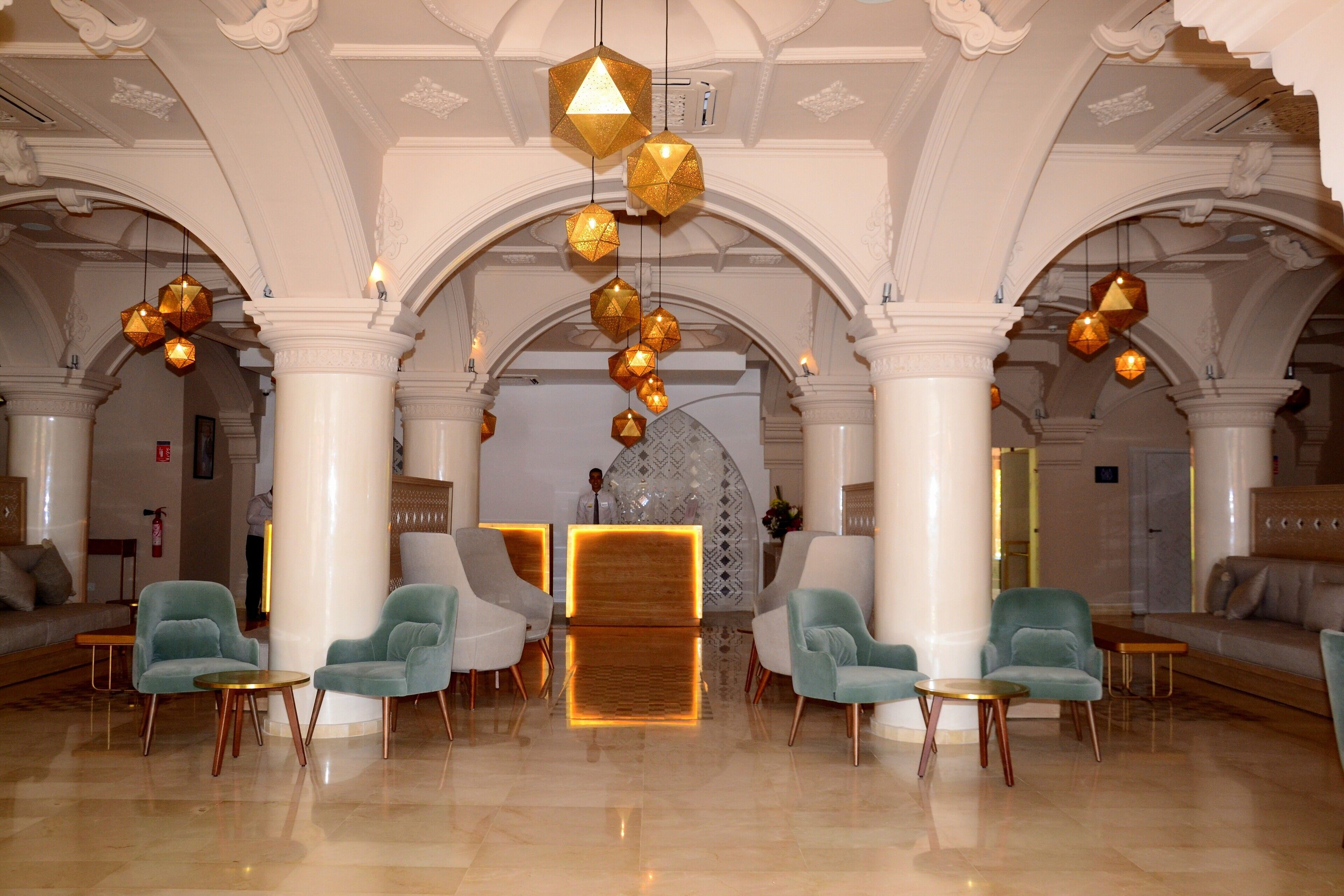 A lobby with a reception desk, seating area, and decorative hanging lights.