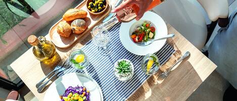Una mesa preparada para una comida con diversos platos, una botella de aceite de oliva y un vaso de agua.