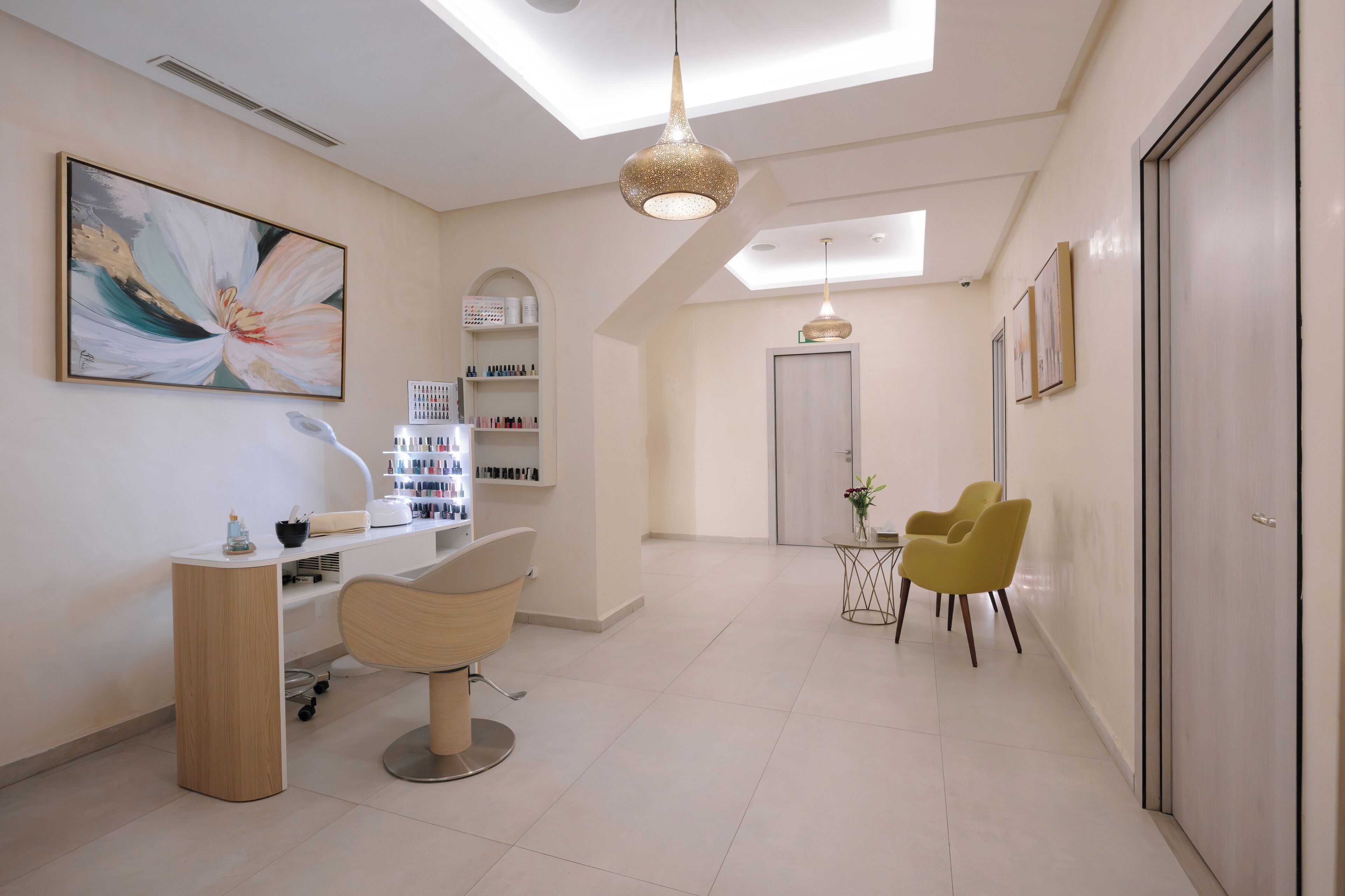 A modern salon with a central reception desk, two chairs, a large abstract painting, and a skylight.