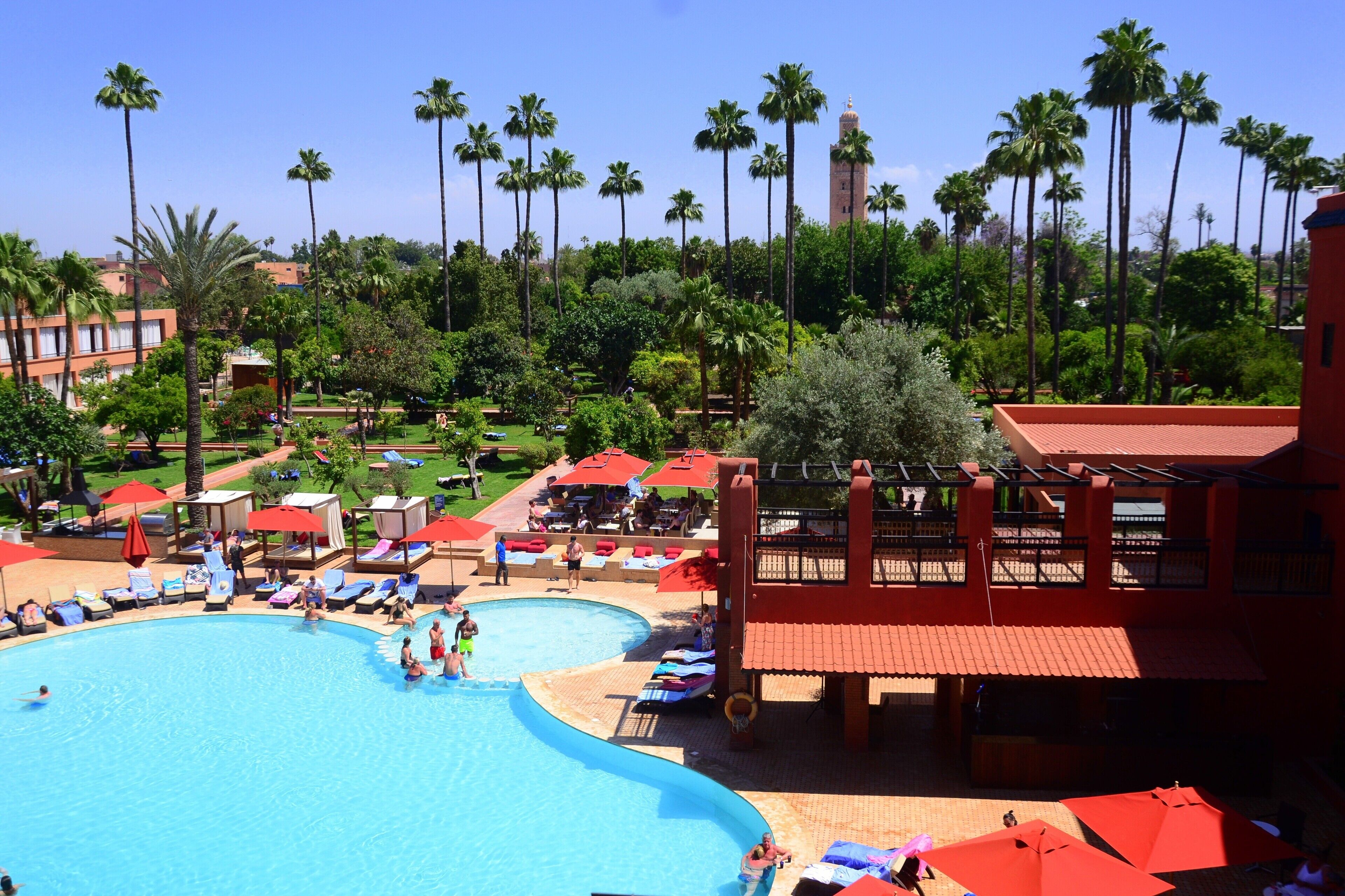 Un resort con una piscina grande, palmeras y edificios de techos rojos.
