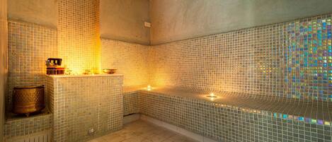 A spa area with mosaic tiled walls and a bench.