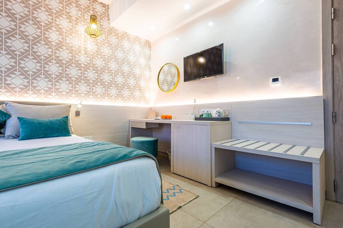 Un dormitorio moderno con cama, mesita de noche, televisor y almacenamiento integrado.