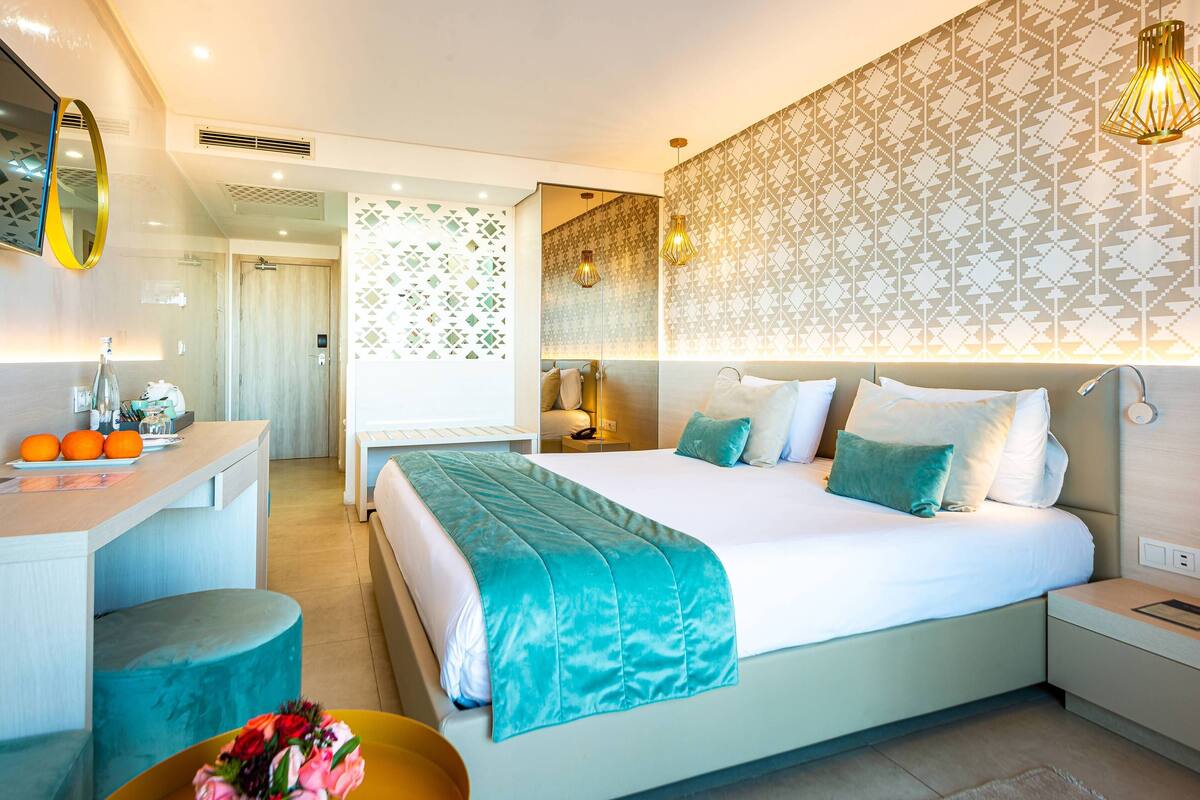 Una habitación de hotel moderna con una cama grande, mesitas de noche, un escritorio y un baño.