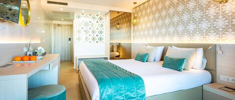 A modern hotel room with a large bed, bedside tables, a desk, and a bathroom.