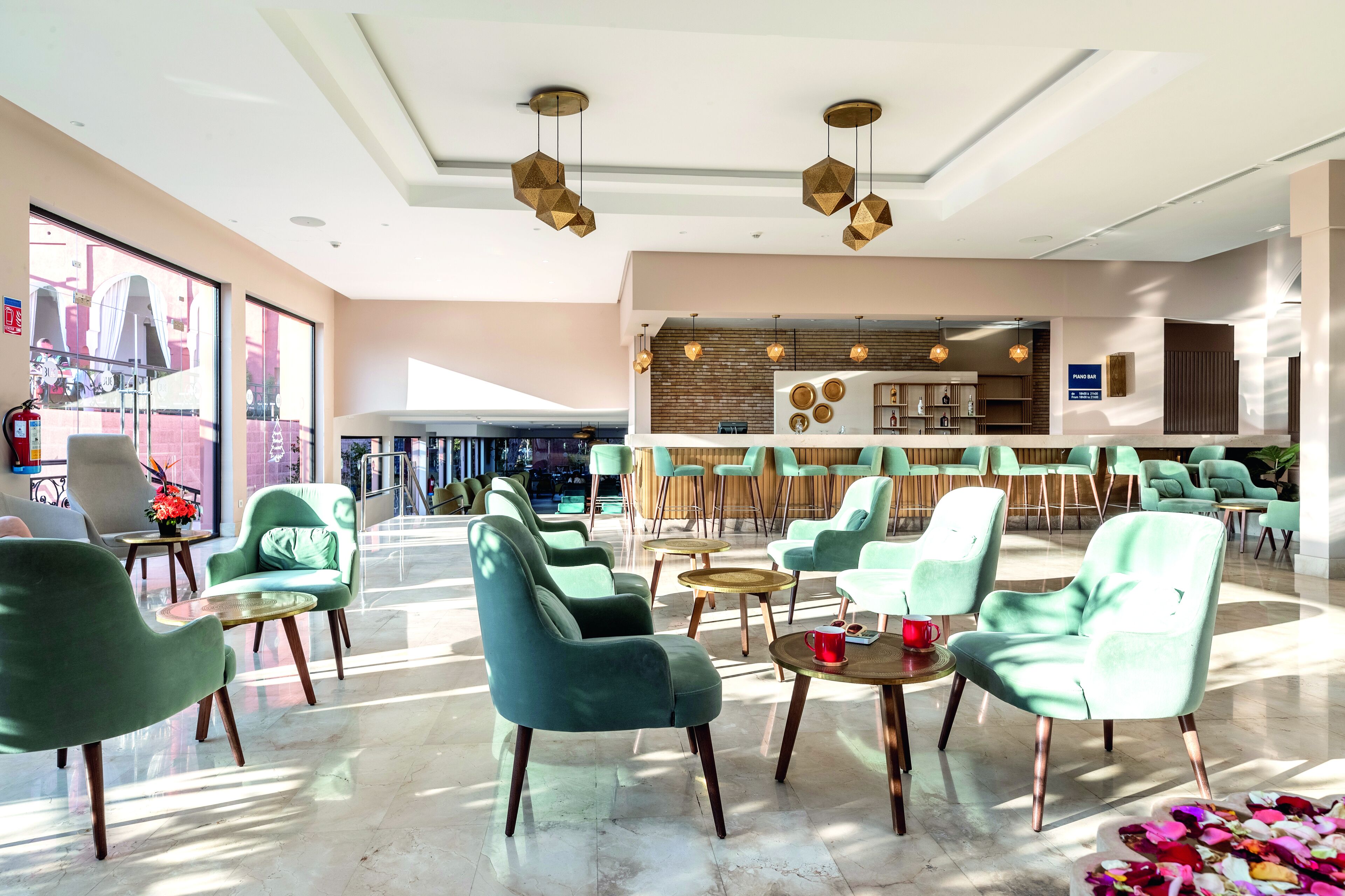 Een ruime lobby met moderne groene stoelen, een bar en grote ramen voor natuurlijk licht.
