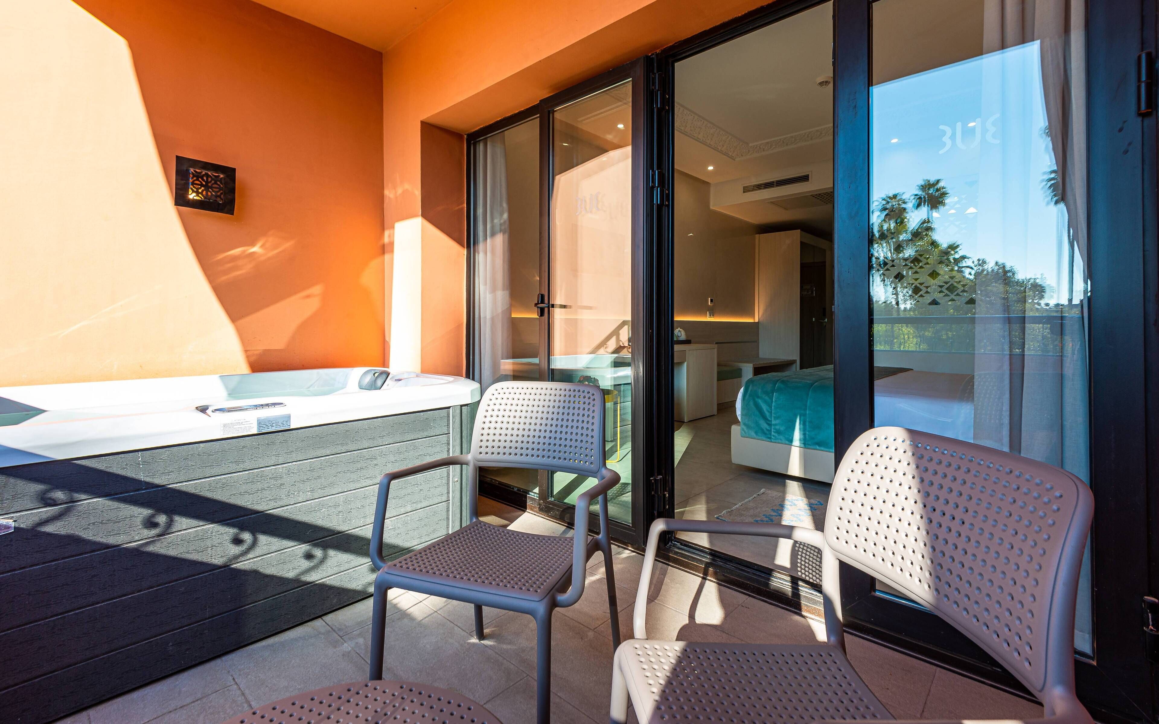 Een balkon met twee stoelen, een tafeltje en een jacuzzi.