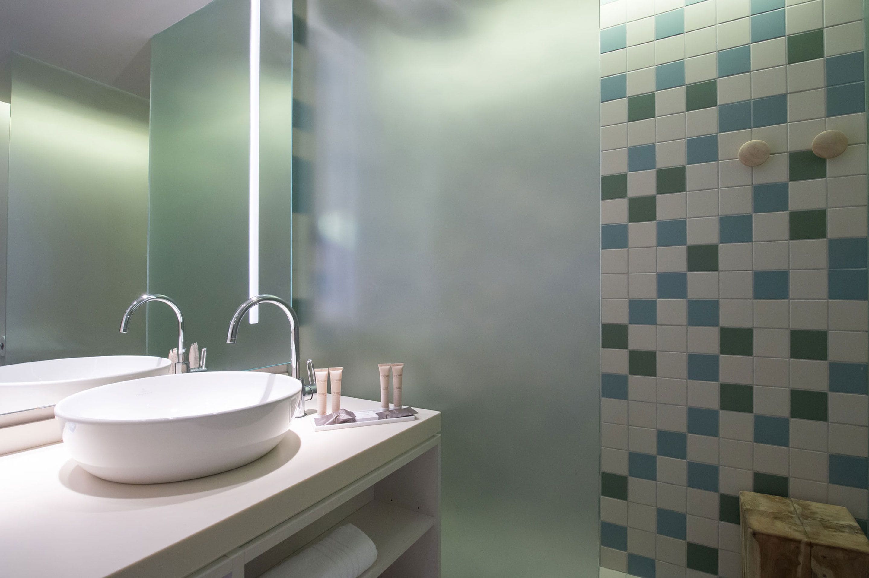 A bathroom with two sinks, a mirror, and a tiled wall.