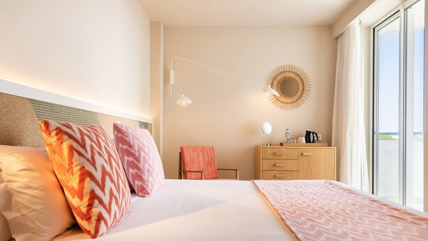Ein Hotelzimmer mit einem großen Bett, einem Schreibtisch, einem Stuhl, einem Spiegel und einem Fenster mit Aussicht.