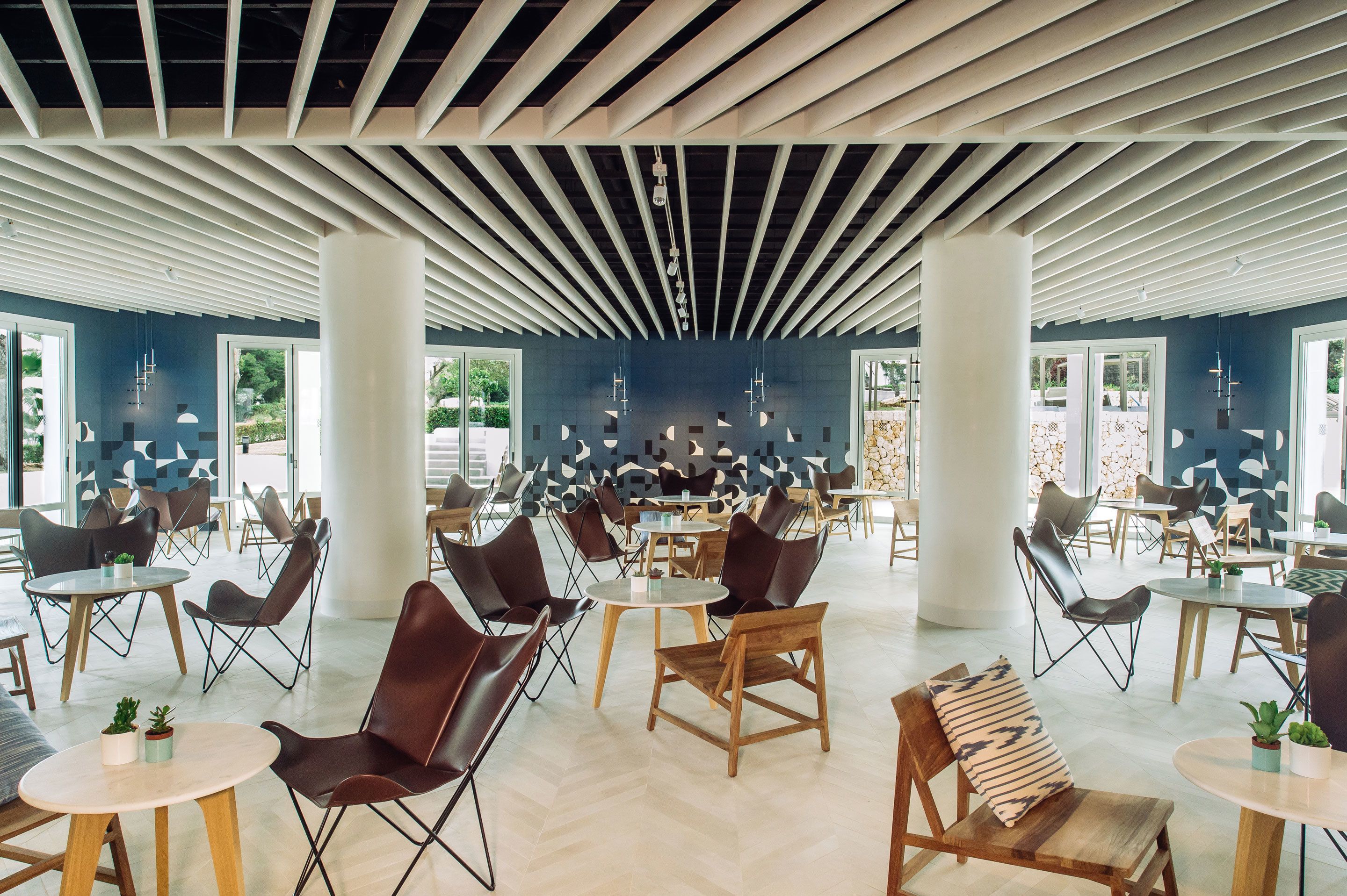 A spacious indoor area with multiple seating arrangements, including tables and chairs, and large windows allowing natural light.