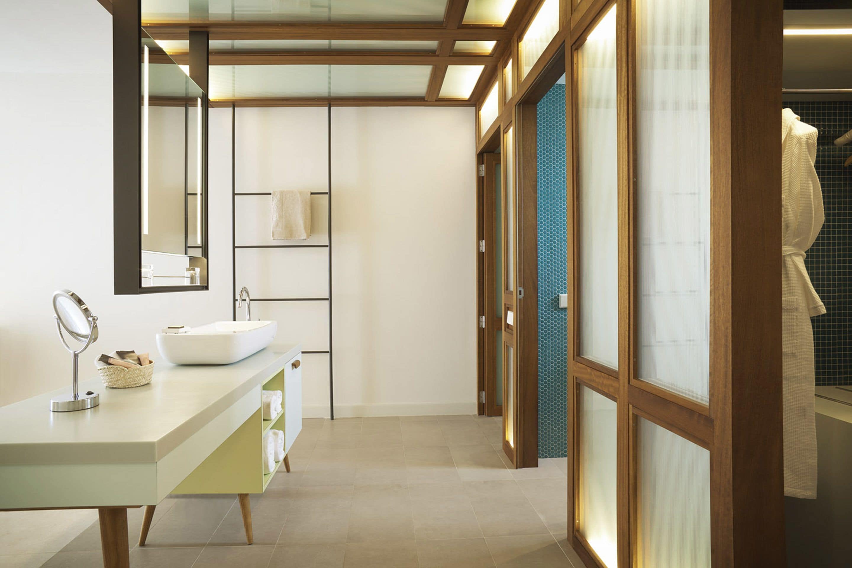 Un baño moderno con un espejo grande, un lavamanos blanco y un perchero para toallas.