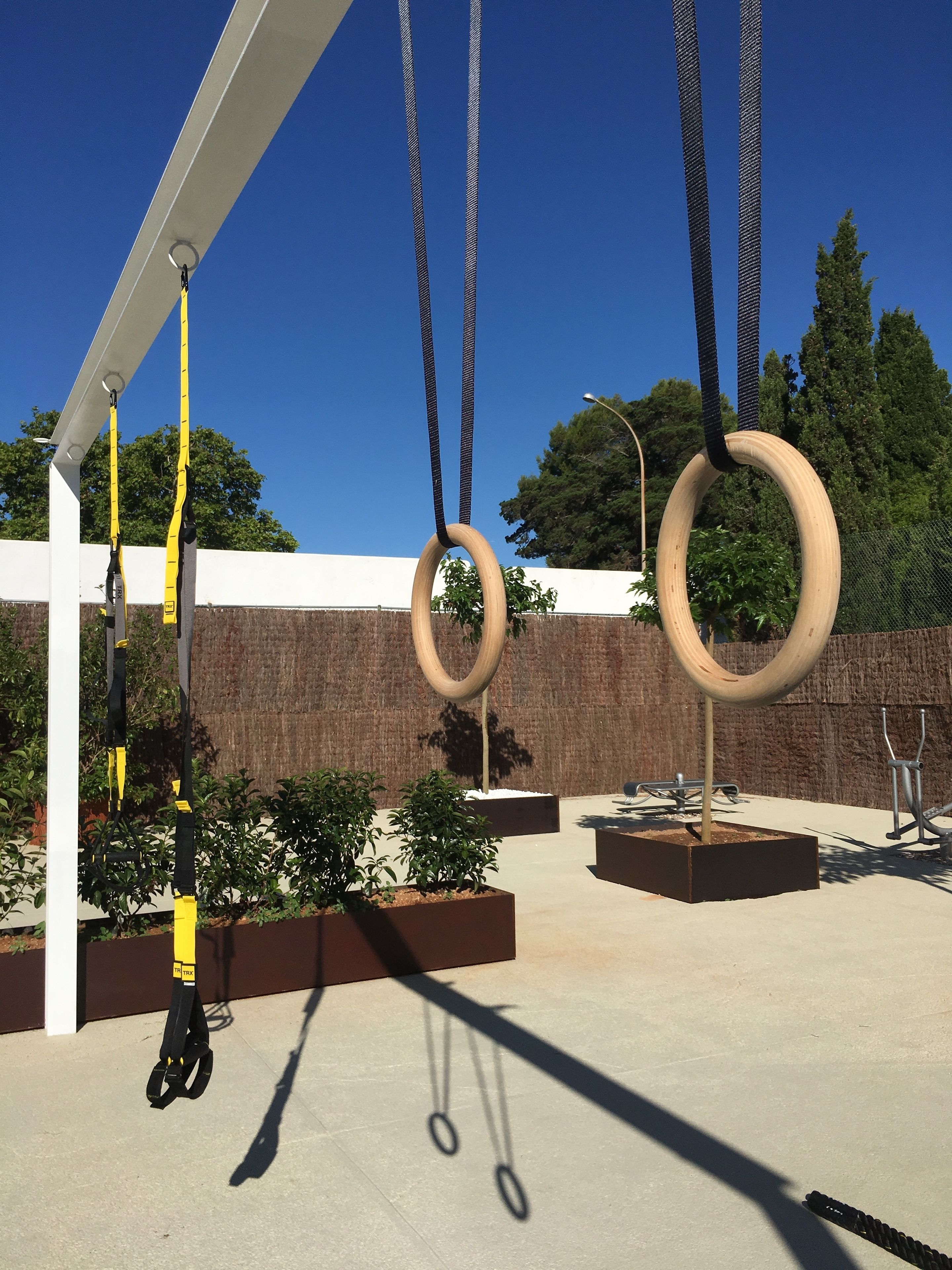 A gym with outdoor exercise equipment, including rings and a pull-up bar.