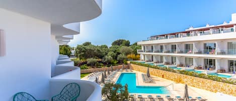 A hotel with a pool area, outdoor seating, and a view of the surrounding landscape.