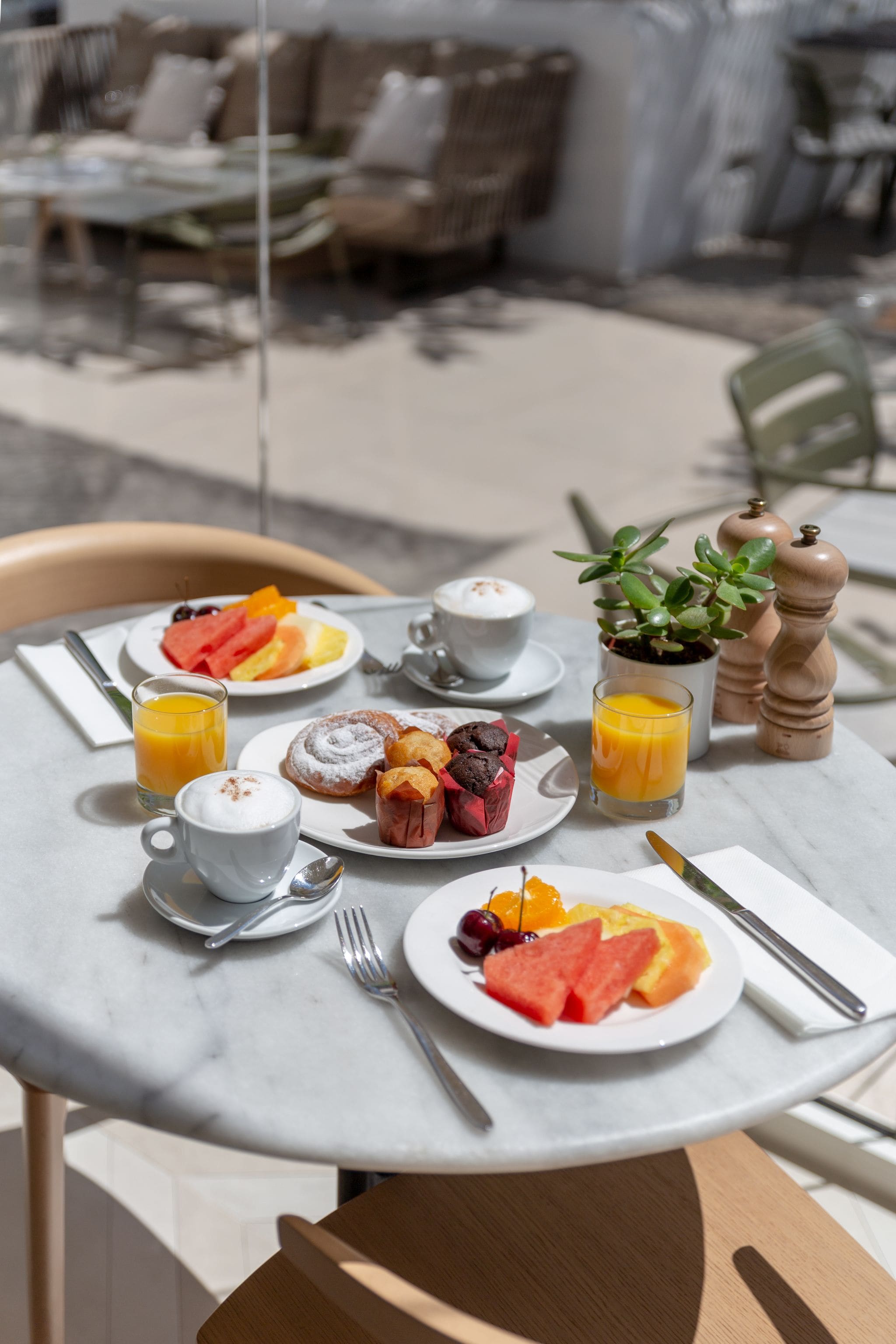 Una mesa de desayuno con platos de comida, una taza de café y un vaso de jugo de naranja.