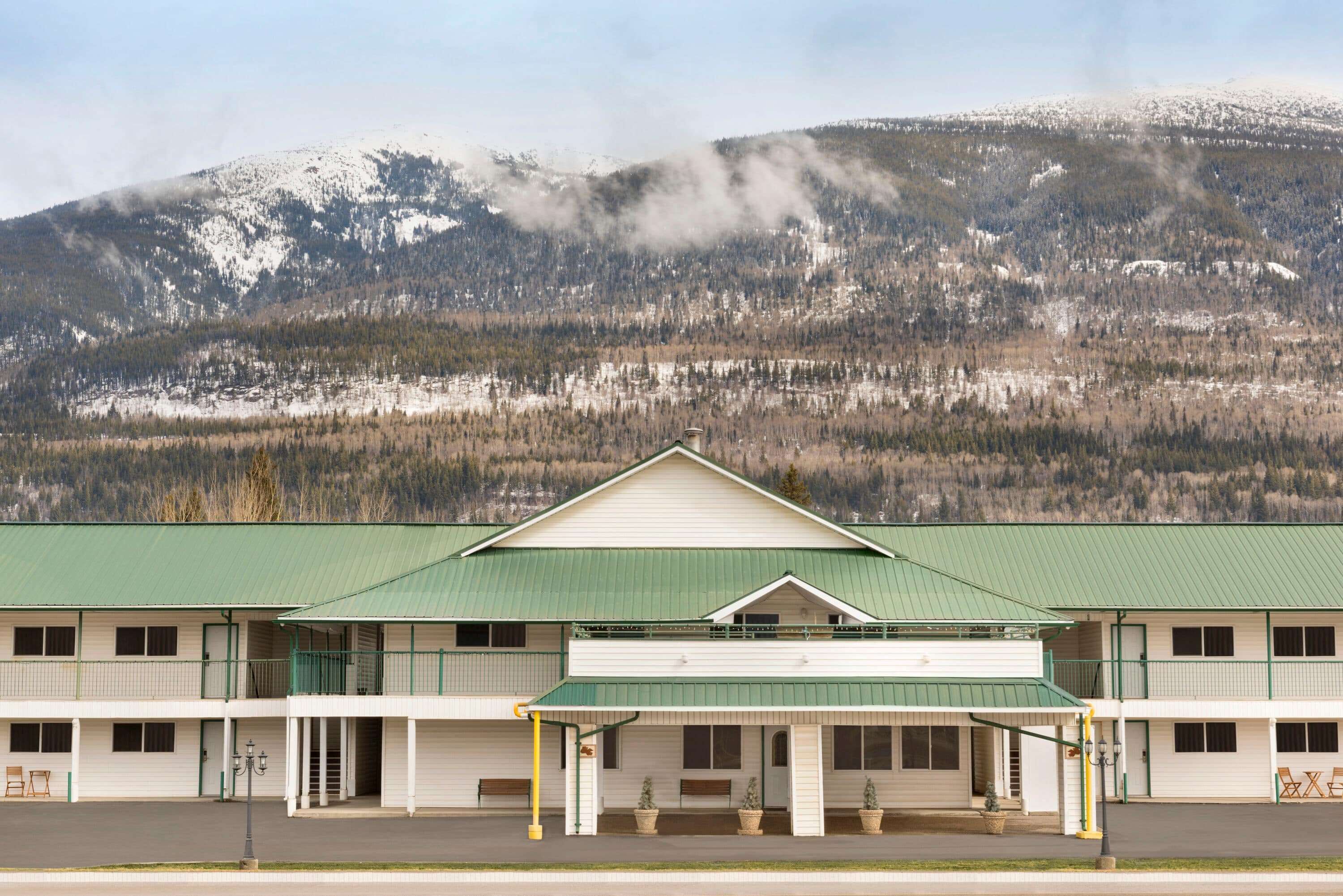 A two-story motel with a green roof and a covered front porch.