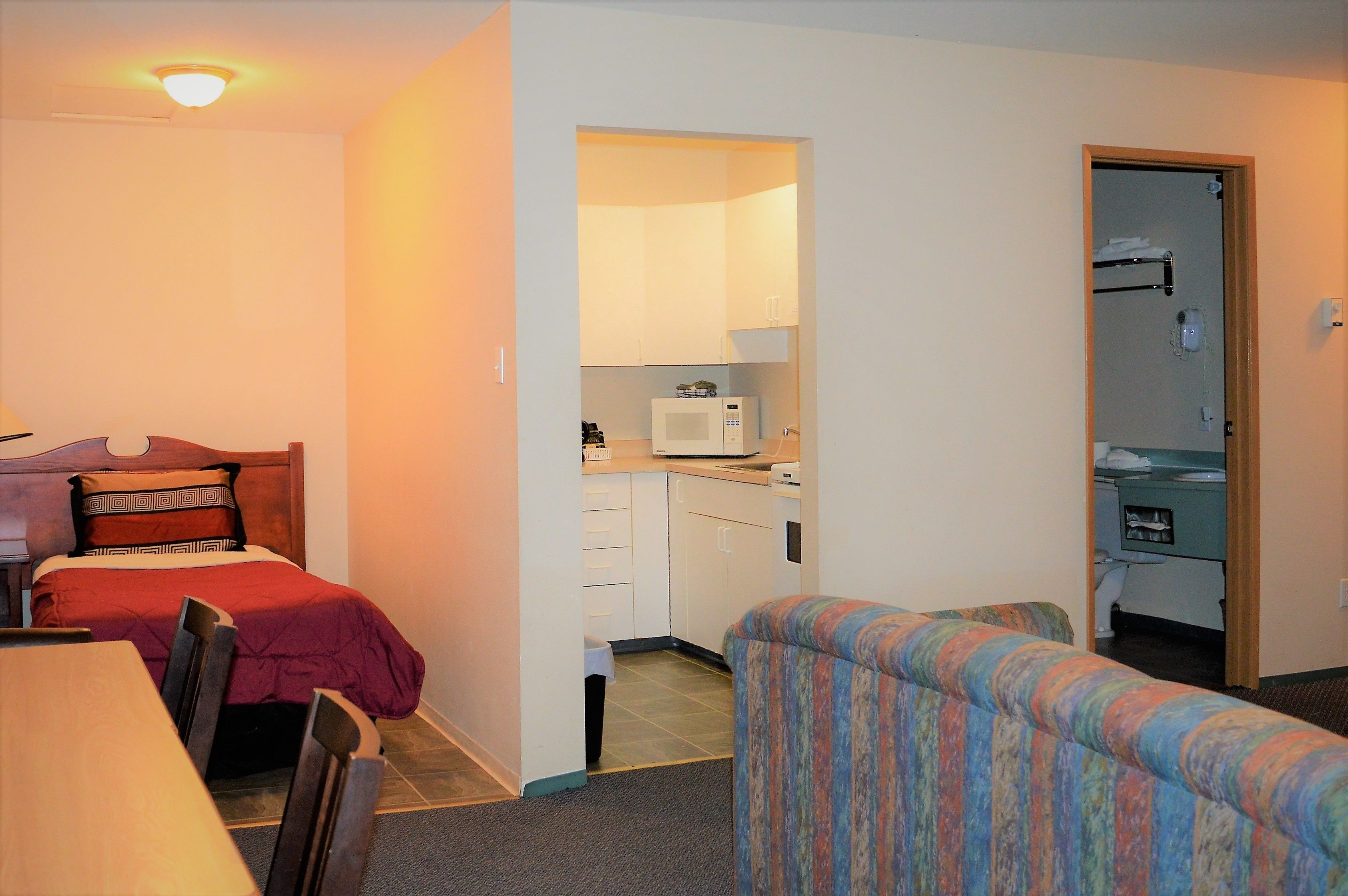 A compact room with a bed, a small kitchenette, a sofa, and a table.