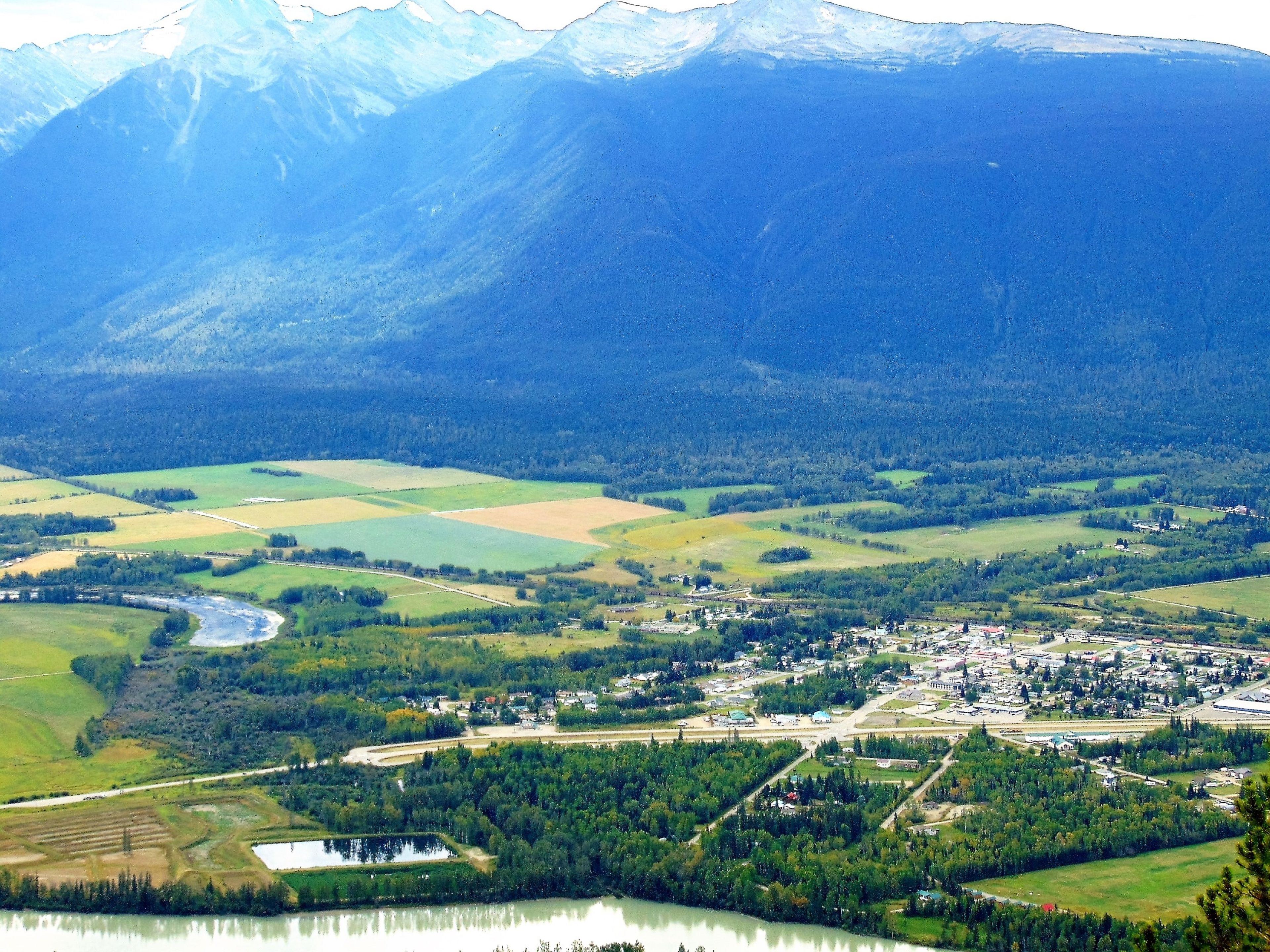 A town with a river, fields, and mountains in the background.