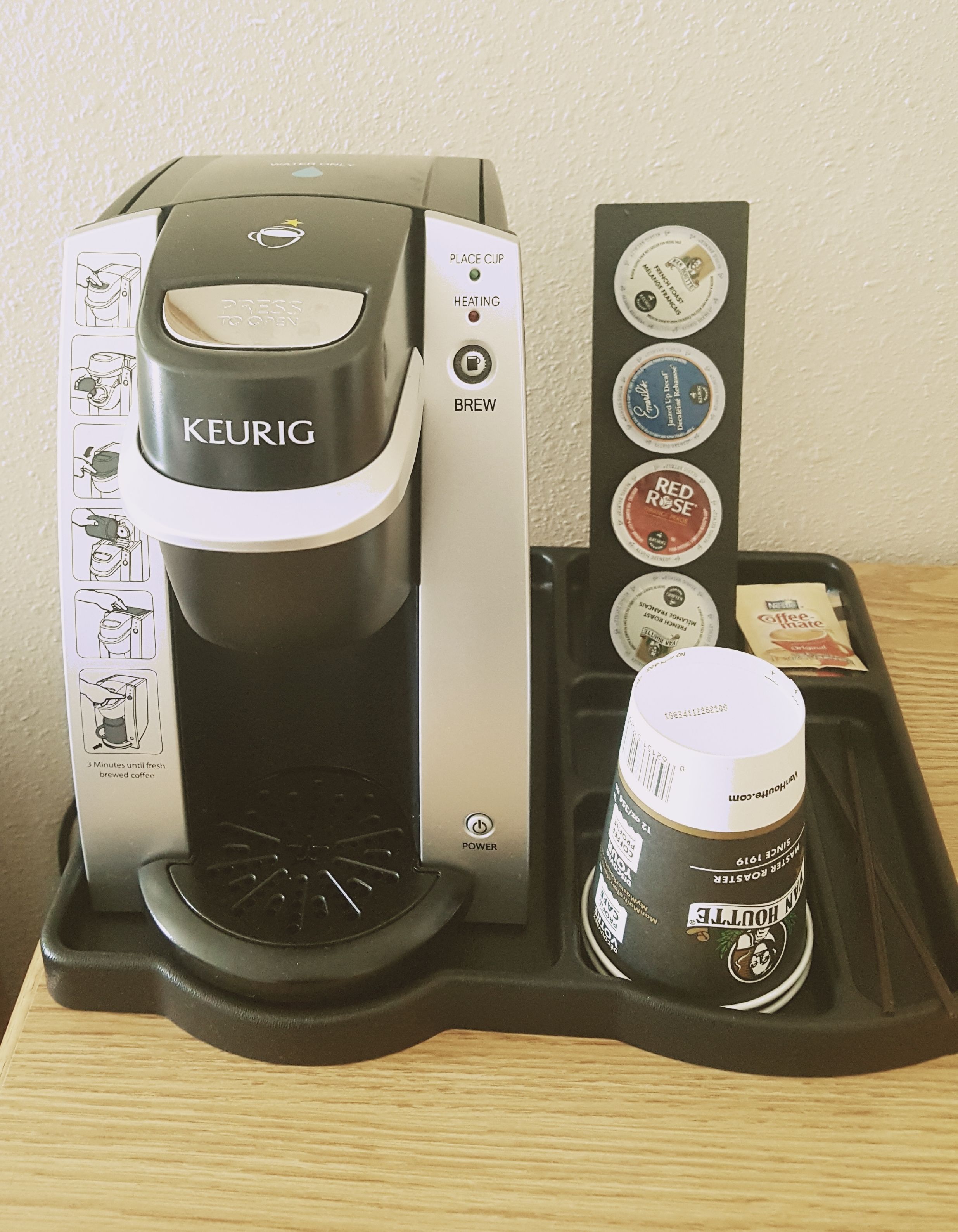 A Keurig coffee maker with a coffee pod holder and a cup of coffee.