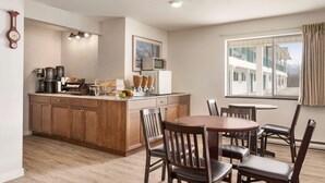 A modern kitchen with wooden cabinets, a central island, and a dining area with wooden chairs.