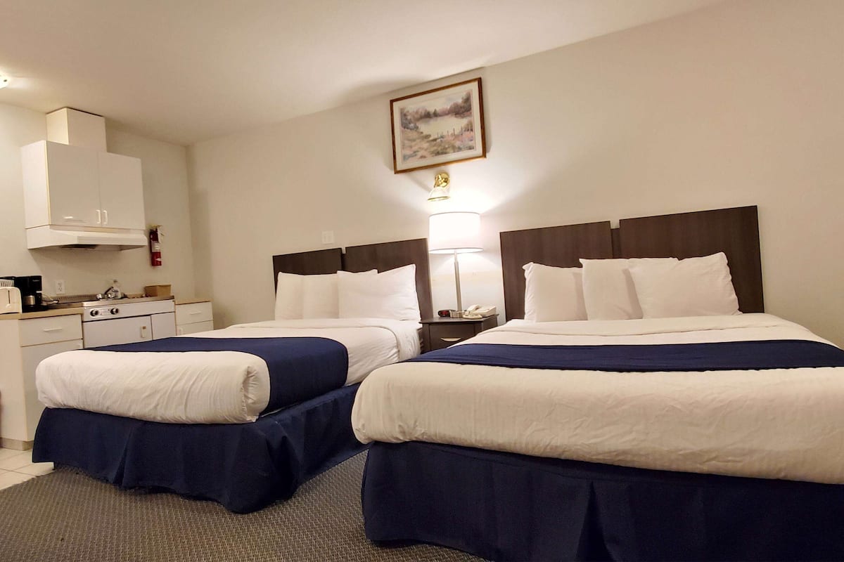 Ein Hotelzimmer mit zwei Betten, einem Schreibtisch und einer Küchenzeile.