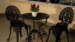 Una terraza en la azotea con una mesa redonda, dos sillas, una planta en maceta y dos faroles.