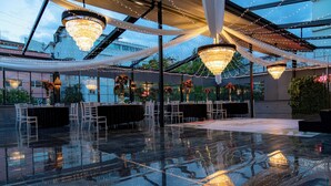 Un espacio interior amplio con suelo reflectante, elegantes candelabros y sillas blancas dispuestas para un evento.
