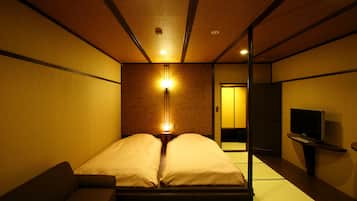 Habitación de hotel con cama, sofá, televisor y lámpara de pared.