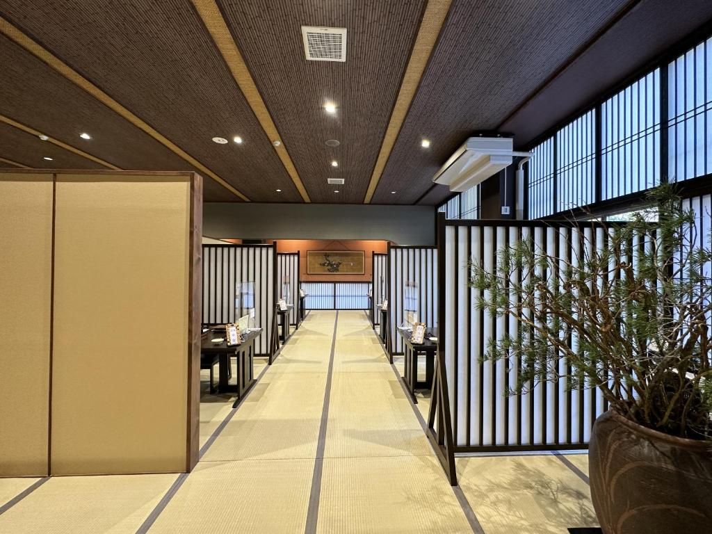 A hotel lobby with a central corridor, seating areas, and a large potted plant.