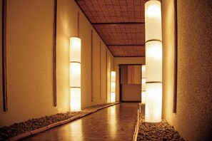 A corridor with a wooden floor, walls with textured surfaces, and cylindrical light fixtures along the walls. - Mount View Hakone (Hakone)
