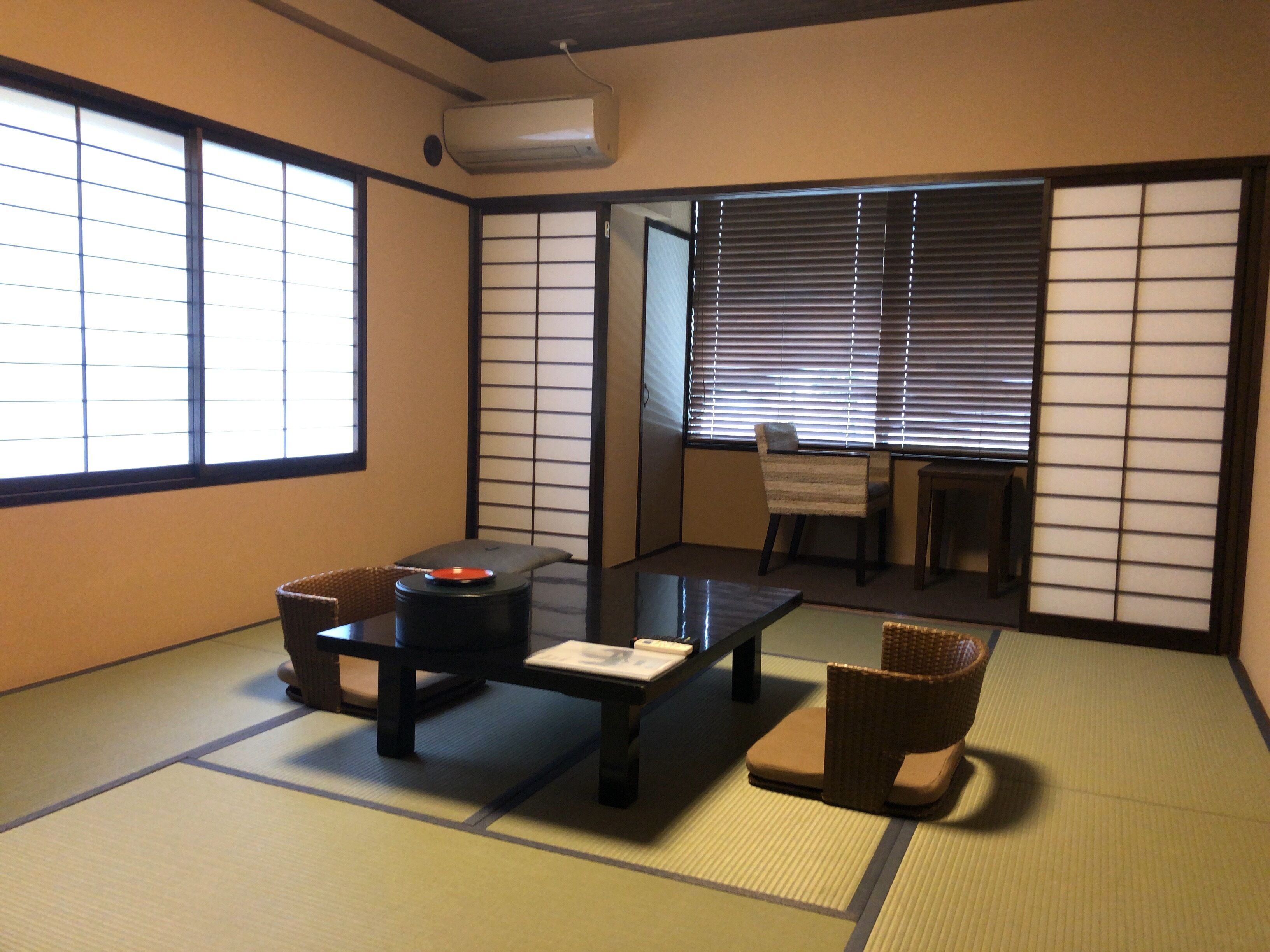 A traditional Japanese room with tatami flooring, a low table, a sofa, and sliding shoji doors.