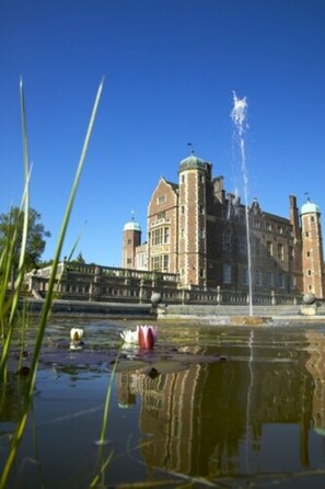 A historic building with a fountain in the foreground, surrounded by water and greenery.