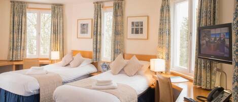 A hotel room with two beds, a desk with a chair, a television, and a phone.