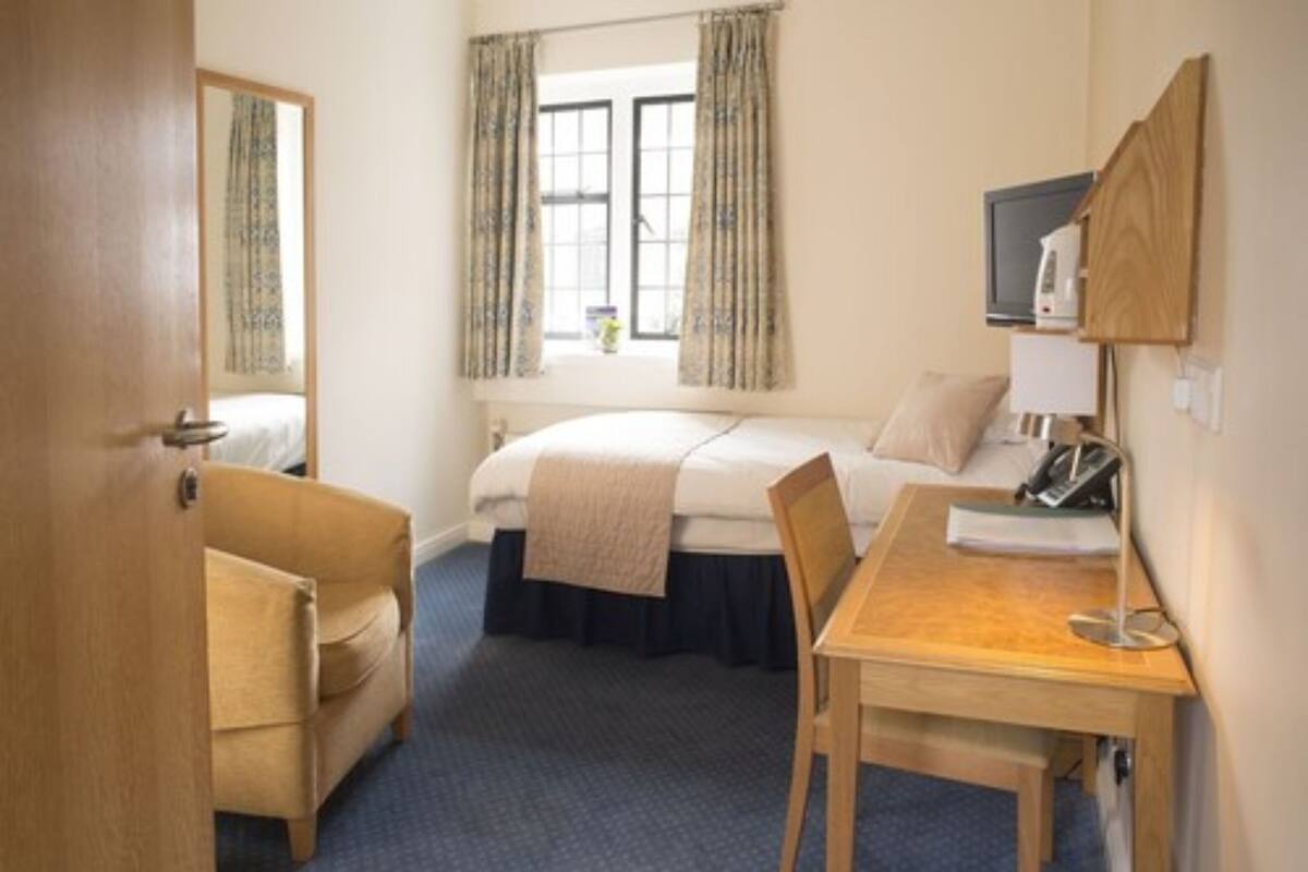 Una habitación de hotel con una cama, un escritorio, una silla, un televisor y una ventana con cortinas.