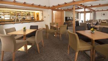 Un vestíbulo de hotel con varias zonas de estar, un bar y una recepción.