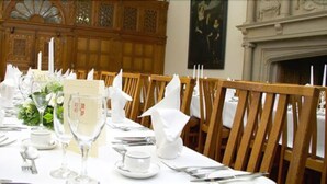 A dining table set for a formal meal with white tablecloths, silverware, and glassware. - Madingley Hall (Cambridge)